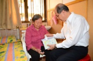 Mr Cheung (right) shows an elderly resident how to use the disinfection gel in the pack.