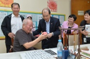 Mr Cheung chats with a resident practising calligraphy activities.