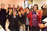 劳工及福利局局长罗致光博士到访明爱郑承峰长者社区中心（深水埗）。图示罗致光博士（左二）向长者送上甜柑预祝农历新年。