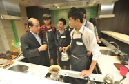 多位參與該中心創出明Teen生涯發展計劃的學員，為張建宗（左）示範咖啡沖調技巧。