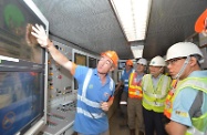 Mr Cheung (second right) is briefed by a representative of Dragages Hong Kong on the operation of the tunnel boring machines. First right is the Commissioner for Labour, Mr Donald Tong.