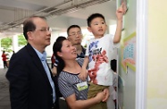 一名儿童向张建宗（左一）介绍他的得奖作品。
