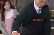勞工及福利局局長羅致光博士到訪香港青年協會「有情廚房」，為「鄰舍第一」社區計劃拍攝短片。圖示羅致光博士（右）為朱古力漿調節溫度。