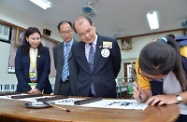 Mr Cheung (third left), Ms Man (first left) and the District Officer (Kowloon City), Mr William Tsui (second left), watch a demonstration of Chinese calligraphy by a Filipino student of the school.
