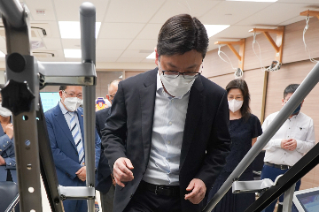 The Secretary for Labour and Welfare, Mr Chris Sun, visited elderly community care and After School Care Programme service centres on September 16 to keep abreast of care services for the young and old. Photo shows Mr Sun (front) trying out how the stair lift gives training to elderly people at Lok Sin Tong Biu Chun Day Care Centre for the Elderly.