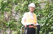 The Secretary for Labour and Welfare, Dr Law Chi-kwong, gives a simulation on the use of safety helmet with Y-type chin straps, reflective vest and step platform for work-above-ground safety.