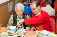 Mr Cheung (right) cuts the food up for an elderly person.