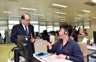 电话热线中心的职员向张建宗（左一）讲解如何处理市民有关低津计划的查询。