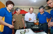 张建宗（中）与潘伟贤（右二）和庄伟茵（左一）到一名计划受惠者家中致送「家电四宝」，并亲手示范用新炉具烹制「煎酿三宝」。
