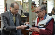 Mr Cheung (left) presents warm clothing items to a single elderly resident in Lok Man Sun Chuen.