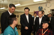 The Chairman of the Standing Committee of the National People's Congress, Mr Zhang Dejiang (centre), is briefed by a physiotherapist on the use of an exoskeleton hand robotic training device in rehabilitation training activities at the Hong Kong Sheng Kung Hui Tseung Kwan O Aged Care Complex in Tseung Kwan O this morning. Joining him are the Chief Executive, Mr C Y Leung (left), and the Secretary for Labour and Welfare, Mr Matthew Cheung Kin-chung (right). 