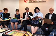 The Secretary for Labour and Welfare, Dr Law Chi-kwong, visited the Adoption Unit of the Social Welfare Department. Photo shows Dr Law (centre) reading a life book prepared by adoptive parents on the lives of their adoptive children. Two secondary school students (second left and second right) enrolled under the "Be a Government Official for a Day" programme to shadow the Secretary also joined the visit.