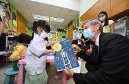 The Secretary for Labour and Welfare, Dr Law Chi-kwong, visited Sweet Heart After School Care Centre for Pre-primary Children in Sham Shui Po this afternoon (September 14) to take a closer look at its re-engineered service, which commenced operation in mid-August. Photo shows a child being cared for by the centre presenting her handicraft work to Dr Law (front, right).