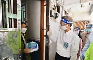 The Secretary for Labour and Welfare, Dr Law Chi-kwong, and the Permanent Secretary for Labour and Welfare, Ms Alice Lau, today (April 4) led their team to distribute anti-epidemic service bags to households in an old building in Kwun Tong District. Photo shows Dr Law (front row, right) appealing to a grassroots household person to self-test each day on April 8, 9 and 10 using the rapid antigen test kits in the bag.