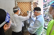 The Secretary for Labour and Welfare, Dr Law Chi-kwong, and the Permanent Secretary for Labour and Welfare, Ms Alice Lau, today (April 4) led their team to distribute anti-epidemic service bags to households in an old building in Kwun Tong District. Photo shows Dr Law (left) putting a collection slip into a household which did not answer the door to collect their service bag from a district distribution point later.