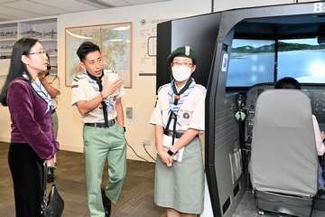 政務司司長陳國基今日(三月十一日)出席香港童軍總會舉辦的「童薈司長 共創明Teen」活動,了解學員及童軍友師就「共創明『Teen』計劃」推展至今的得着。勞工及福利局常任秘書長劉焱亦有出席。圖示劉焱(左一)聽取童軍介紹航空訓練。