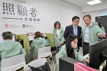 勞工及福利局局長孫玉菡今日(九月二十七日)上午到訪照顧者支援專線中心,視察專線自昨日(九月二十六日)凌晨零時投入服務至今的運作情況。勞工及福利局康復專員王秀慧亦有同行。社會福利署委聘東華三院營辦24小時照顧者支援專線182 183。圖示孫玉菡(站立,右二)聽取東華三院社會服務科主管婁振陽(站立,右一)匯報照顧者主要的需要及專線社工提供的服務。