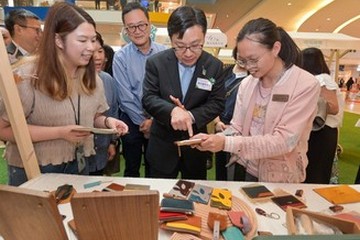 勞工及福利局局長孫玉菡今日(十一月三日)下午為賽馬會共融.知行計劃共融就業市集暨展覽2023主禮。圖示學員向孫玉菡(前排中)介紹殘疾人士透過職業康復訓練製作的手作皮革產品。