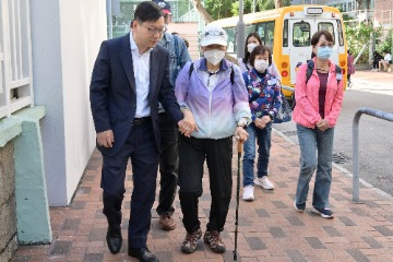 劳工及福利局局长（劳福局）孙玉菡今日（十二月十日）上午率领劳福局及社会福利署（社署）义工队到访荃湾乐善堂尹立强敬老邻舍中心，视察社署一笔过资助长者中心提供便利长者于二○二三年区议会一般选举投票措施。图示孙玉菡（前排左）陪伴长者前往票站。