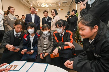 政務司司長兼扶貧委員會主席陳國基今日(十二月十八日)視察深水埗社區客廳,是「社區客廳試行計劃」首個項目。勞工及福利局局長孫玉菡亦有隨行。圖示陳國基(站立,前排左二)和孫玉菡(站立,前排左三)參觀共享客廳,觀看學生玩遊戲。