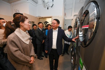 政務司司長兼扶貧委員會主席陳國基今日(十二月十八日)視察深水埗社區客廳,是「社區客廳試行計劃」首個項目。勞工及福利局局長孫玉菡亦有隨行。圖示陳國基(前排右一)參觀自助洗衣站,了解設施如何便利「劏房」戶。