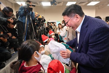 The Chief Secretary for Administration and Chairperson of the Commission on Poverty, Mr Chan Kwok-ki, today (December 18) officiated at the Sham Shui Po Community Living Room Opening Ceremony, the first project under the Pilot Programme on Community Living Room. The Secretary for Labour and Welfare, Mr Chris Sun, also attended. Photo shows Mr Chan (first right) presenting Christmas gifts to children.