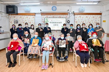 勞工及福利局局長孫玉菡今日(十二月二十日)到訪上環一間安老院,了解院舍外展疫苗接種服務特別計劃的推行情況。圖示孫玉菡(站立,右六)及東華三院主席韋浩文(站立,左六)與院友合照。