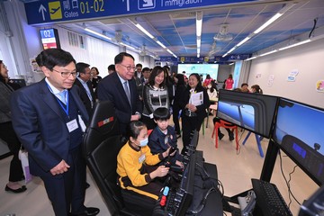 The Chief Secretary for Administration, Mr Chan Kwok-ki, today (March 14) chaired the fifth meeting of the fifth-term Commission on Poverty and led members to visit a school participating in the School-based After School Care Service Scheme to observe its operations. The Secretary for Labour and Welfare, Mr Chris Sun; the Under Secretary for Home and Youth Affairs, Mr Clarence Leung; and the Under Secretary for Education, Mr Jeff Sze, also joined the visit. Photo shows Mr Chan (standing, front row, second left) and Mr Sun (standing, front row, first left) watching students on a flight simulator in the STEM (science, technology, engineering and mathematics) room.