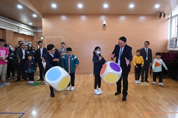 政务司司长陈国基今日（三月十四日）主持第五届扶贫委员会第五次会议，并率领委员探访参与在校课后托管服务计划的学校，实地视察计划运作。劳工及福利局局长孙玉菡、民政及青年事务局副局长梁宏正和教育局副局长施俊辉亦有随行。图示陈国基（前排右一）和孙玉菡（前排右四）与学童玩游戏。