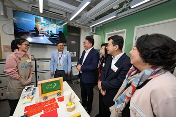 政務司司長陳國基今日（二月九日）主持西營盤社區客廳開幕典禮。勞工及福利局局長孫玉菡、周大福慈善基金理事紀文鳳、利希慎基金總裁何宗慈、勞工及福利局常任秘書長劉焱、社會福利署署長杜永恒和香港明愛總裁閻德龍神父亦一同主禮。圖示陳國基（左三）和孫玉菡（右二）與正在製作絲網印刷利是封的用戶交流。