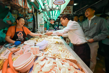 政府长者及合资格残疾人士公共交通票价优惠计划（二元优惠计划）今日（四月三日）起由二元划一收费调整为「两蚊两折」。劳工及福利局局长孙玉菡今日到黄大仙及调景岭视察「两蚊两折」首日实施情况。图示孙玉菡（中）在黄大仙大成街街市，向街市档贩派发「两蚊两折」宣传单张。