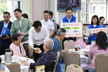 政府长者及合资格残疾人士公共交通票价优惠计划（二元优惠计划）今日（四月三日）起由二元划一收费调整为「两蚊两折」。劳工及福利局局长孙玉菡今日到黄大仙及调景岭视察「两蚊两折」首日实施情况。图示孙玉菡（前排左二）在黄大仙一间酒家，向市民介绍二元优惠计划的收费调整。