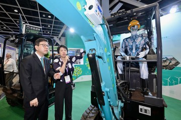 由劳工处和职业安全健康局（职安局）合办的职安健创科博览今日（六月二日）揭幕。图示劳工及福利局局长孙玉菡（左）听取职安局总干事游雯（右）介绍纯电遥控挖土机的操作。