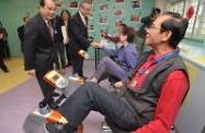 Mr Cheung (left) tours around the Bliss District Elderly Community Centre and encourages the centre users to make good use of the new fitness equipment there.