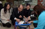 Mr Cheung (second left) plays with a baby while visiting the childcare facilities of the home.