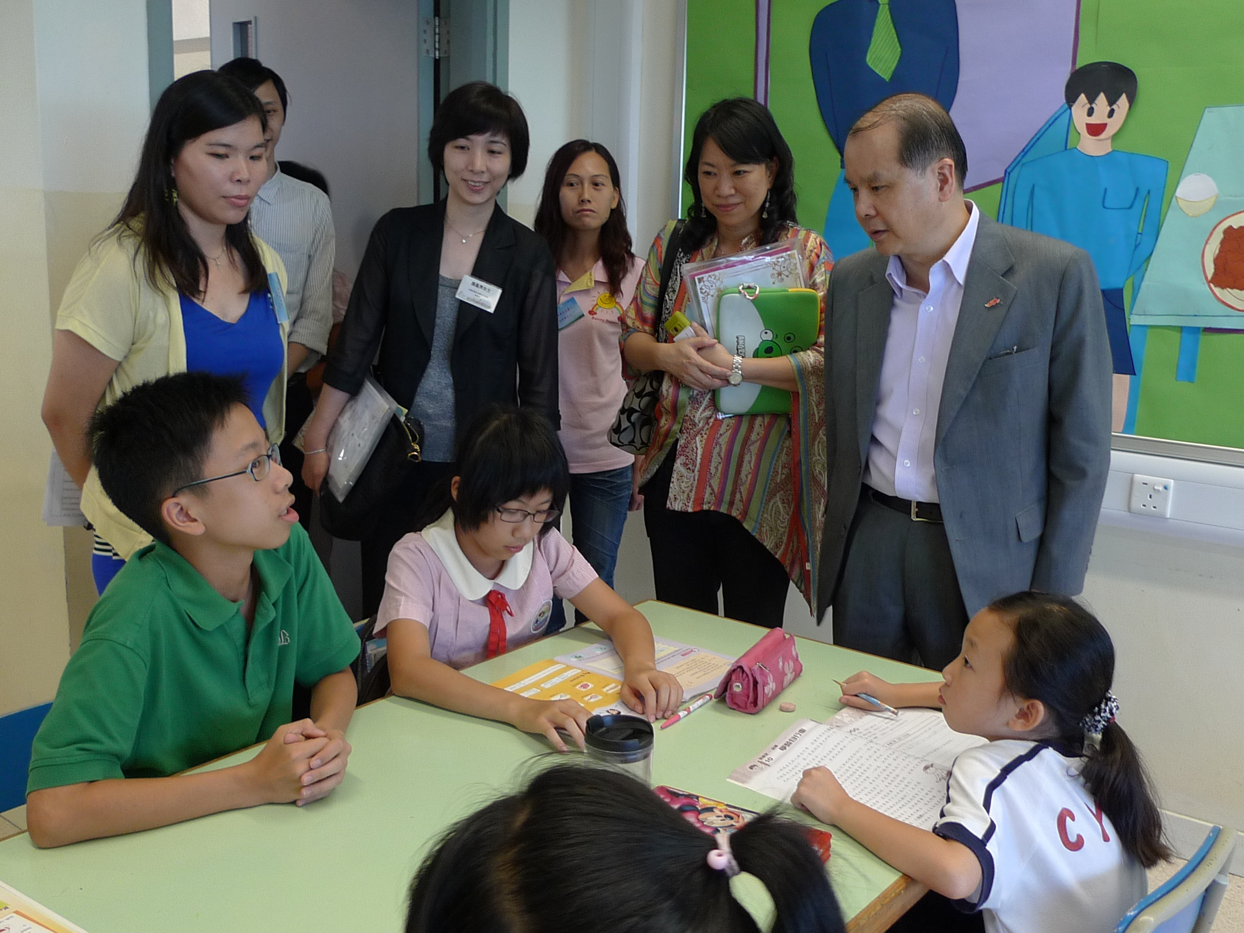 張建宗參觀天水圍「晴天計劃」下的校園託管服務，並與幫助小朋友溫習的中學生義工傾談。