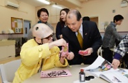 Mr Cheung (centre) extends Lunar New Year greetings to a resident and expresses his appreciation of the talented man's artworks.