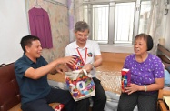 劳工及福利局局长罗致光博士（中）到元朗区参与「共庆回归显关怀」计划的家访活动，探访长者，并致送礼物包。